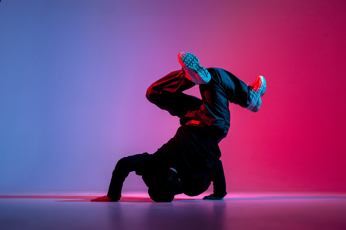 dancer doing acrobatic trick dancing breakdance neon red blue lighting
